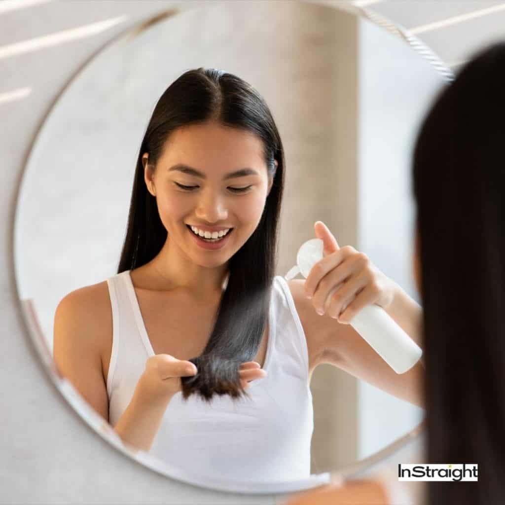 lady spraying her hair with dry shampoo